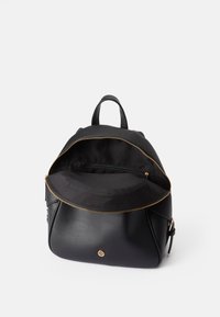 Fekete bőr hátizsák arany cipzárral, texturált külső borítással és fekete szövet belső térrel. Elülső zsebbel és felső fogantyúval rendelkezik.