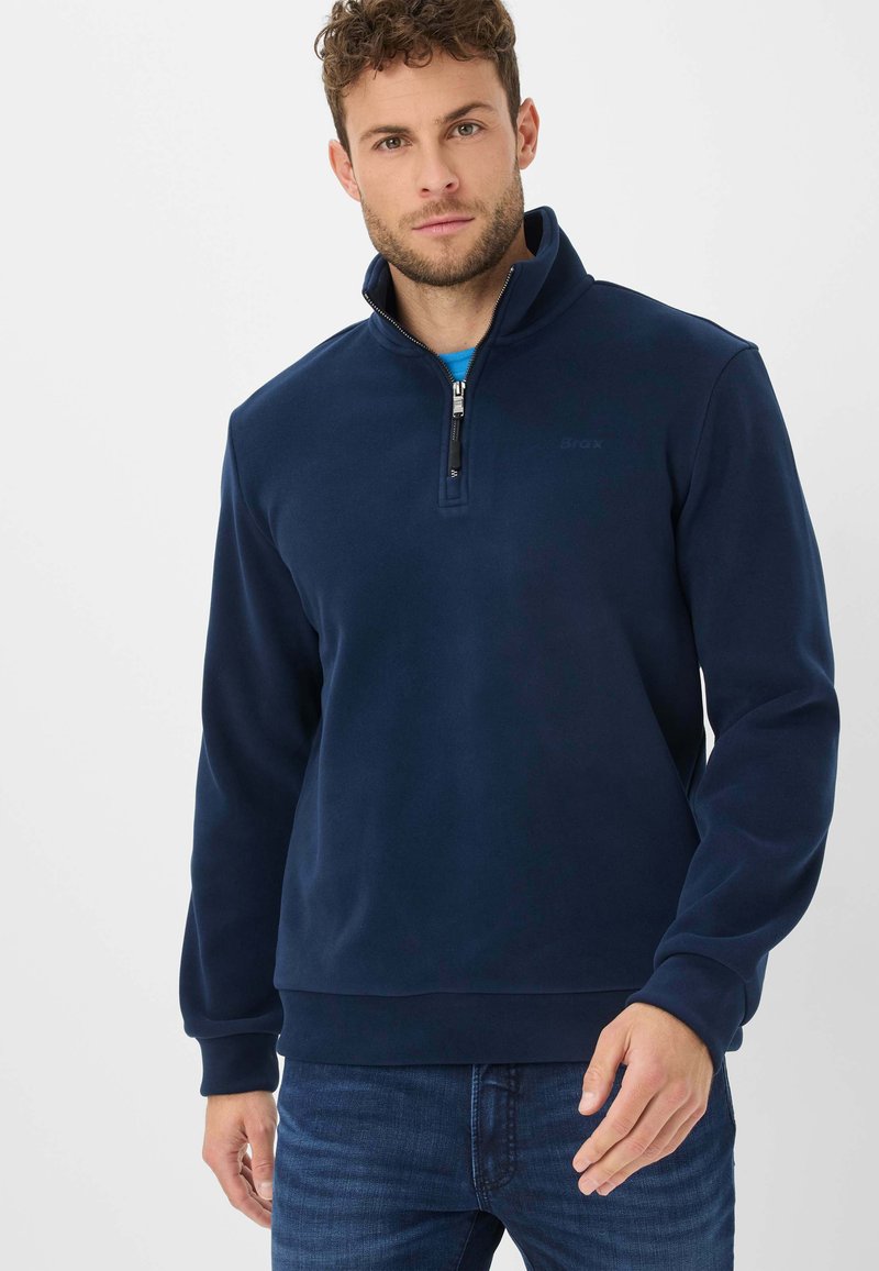 Pullover in pile blu navy con colletto a mezzo zip, maniche lunghe e polsini a costine. Texture liscia, con un logo discreto sul petto.