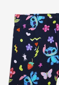 Rekbare marineblauwe legging met kleurrijke cartoonfiguren en speelse patronen, waaronder harten, bloemen, sterren en bliksemflitsen.