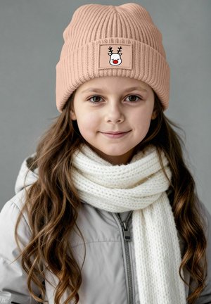 Pink ribbed knit beanie with a reindeer face patch; paired with a thick white knitted scarf. Model wears a light gray jacket.