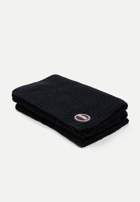 Fular tricotat de culoare bleumarin, împăturit în două straturi. Prezintă o textură striată și un patch logo circular în nuanțe de vișiniu și alb pe o margine.