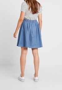 Vaaleansininen farkkuhame, jossa on kerätty vyötärö, levenevä muoto ja polvimittainen helma. Yhdistetty valkoisen ja tummansinisen raidallisen paidan sekä valkoisten lenkkareiden kanssa.