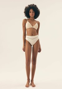 Weißes, geripptes Bikini-Oberteil mit verstellbaren Trägern und dazu passendem hochgeschnittenem Höschen mit einem strukturierten Bund. Glattes Material und minimalistisches Design.