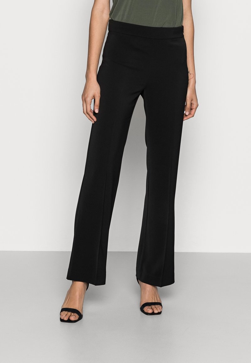 Svarta vida byxor i ett mjukt material med hög elastisk midja. Matchade med svarta sandaler med öppen tå.