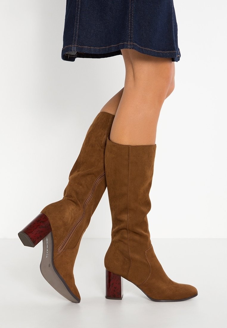Bottes hauteur genou en daim marron avec un bout carré et une surface texturée, dotées d'un talon chunky stylé avec un accent rouge et d'un détail de couture latérale.