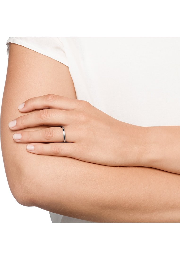 Silverring med en slät, glänsande yta, bärs på en hand som vilar på en arm. Ringen är enkel, rund och utan prydnader.