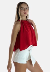 Rode halterneck top met een losse fit en een geraffineerde halslijn, gecombineerd met witte denim shorts met rafelige zoom en een belted taille.