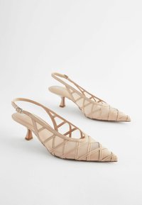 Beige slingback hæle med spids tå, krydspåførte stropper og en lille blokhælkappe. Fremstillet af glat materiale med et elegant design.