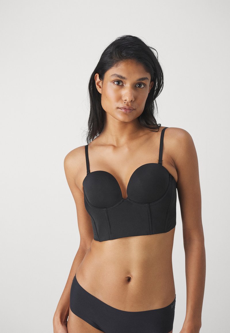 Svart bustier bh med glatt stoff, strukturerte skåler og justerbare tynne stropper. Har en V-hals og et tettsittende, cropped design.