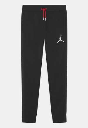 Black athletic pants with red drawstring and white Jumpman logo on right thigh, featuring cuffed ankles and side pockets.