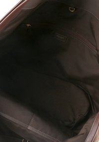 Notranjost rjave usnjene torbice z gladko teksturo, opremljena z žepom z zadrgo in tekstilno podlogo, zasnovana za prostorno organizacijo.