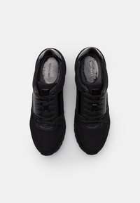 Baskets noires présentant un mélange de mesh et de daim, avec un bout arrondi, un design à lacets et des accents élégants en cuir verni au niveau du talon.