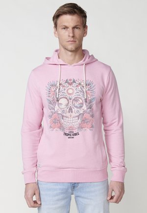 Sudadera rosa de algodón, con un gráfico de una calavera rodeada de flores tropicales y el texto "TROPIC VIBES" en la parte inferior.