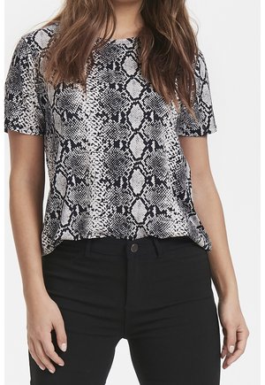 Halenka s krátkým rukávem v černo-bílem hadím vzoru, s volným střihem a hladkým materiálem, zkombinována s černými kalhotami.