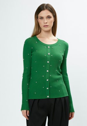 Groene geribbelde cardigan met lange mouwen, een ronde hals, een voorknoopsluiting en versierd met zilveren bloemenachtige accenten doorheen.