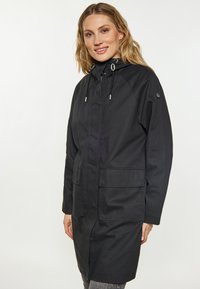 Cappotto nero da esterno con zip frontale, cappuccio con cordino e due tasche anteriori. Realizzato in un tessuto liscio e resistente all'acqua.