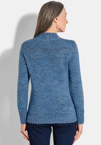 Blauer, gestrickter Pullover mit hohem Kragen, langen Ärmeln und gerippten Bündchen. Der Stoff hat ein strukturiertes, variierendes blaues Muster.