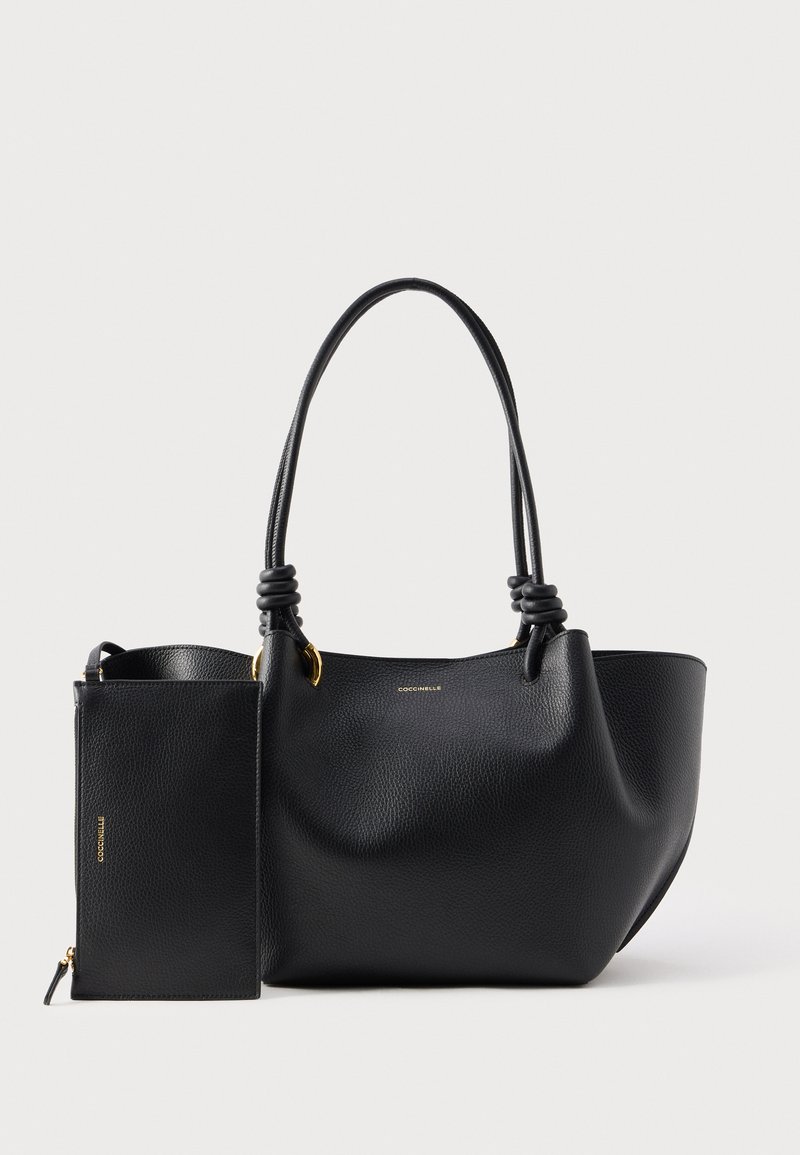 Μαύρη τσάντα χειρός από δερματόνημα με υφή, δύο λαβές με κόμπους και αντίστοιχο ορθογώνιο νεσεσέρ με φερμουάρ, και τα δύο με μικρές χρυσές λεπτομέρειες λογότυπου.