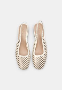 Zapatos slingback beige con un diseño de rejilla, hechos de material sintético suave. Presentan un interior liso y acolchado y punta abierta.