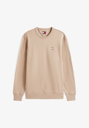Sudadera beige de manga larga, con puños y dobladillo acanalados, cuello redondo, que presenta un pequeño parche de logo en el lado izquierdo del pecho. Textura suave.
