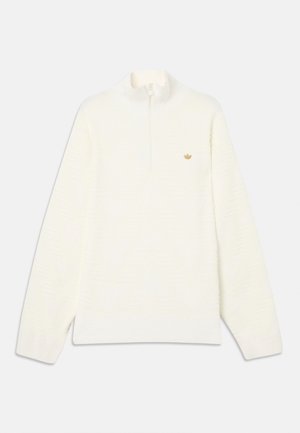 Pull-over blanc à manches longues avec une fermeture éclair quart de longueur et un petit logo beige sur le côté gauche de la poitrine, présenté sur un fond clair uni.