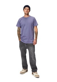 Lilla bomulds T-shirt med rund hals, korte ærmer, kombineret med grå denim jeans og beige sneakers med brune detaljer. Enkel design og pasform.
