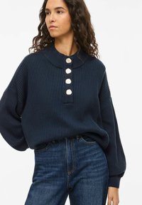 Maglione a coste blu navy con collo e cinque bottoni decorativi color crema sulla patta. Vestibilità rilassata, maniche lunghe e tessuto morbido.