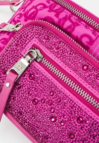 Vaaleanpunainen olkalaukku, jossa on teksturoitu pinta, useita vetoketjullisia osastoja ja koristeellisia läpinäkyviä helmiä. Varustettu hopeisilla osilla ja hihnoilla.