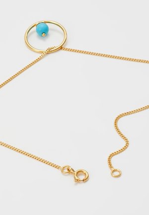 Collier chaîne en or avec fermoir rond et pendentif circulaire orné d'une perle turquoise sur un fond uni clair.