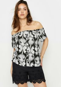 Top de hombros descubiertos en tela negra con un patrón paisley blanco; cuenta con un escote fruncido y mangas cortas. Combina con pantalones cortos negros de dobladillo festoneado.