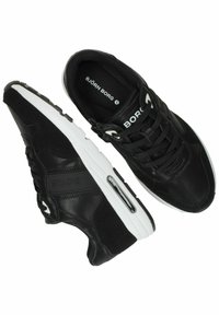 Zwarte sportschoenen van een mix van glad leer en gestructureerd suede. Beschikt over een witte tussenzool, zwarte veters en logo-details aan de zijkant.