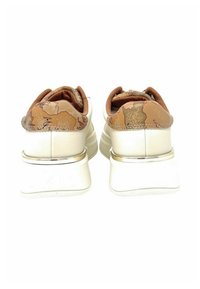 Sneakers bianche con una parte posteriore color sabbia testurizzata e decorata, caratterizzate da un collo imbottito e un accento argento sul tallone. Design della suola spesso.