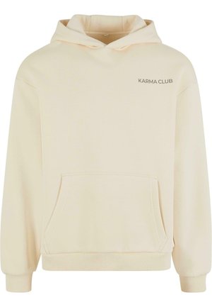 Creme hoodie med kængurulomme, ribbede ærmer og kant. Har "KARMA CLUB" logo i et diskret print på venstre side. Blød tekstur.