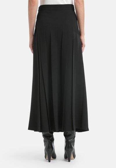 Fustă plisată neagră dintr-un material neted, având un tiv înalt. Asortată cu cizme negre cu toc strâmte pentru un aspect elegant.