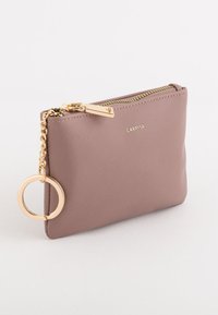 Cartera de cuero texturizado rosa con cremallera dorada, detalle de cadena y llavero metálico redondo. Logo estampado en la parte frontal. Forma rectangular.