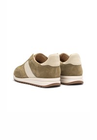 Sneakers in suede verde oliva con dettagli crema, forma arrotondata e suole imbottite. La vista posteriore mette in evidenza il materiale texturizzato e le cuciture.