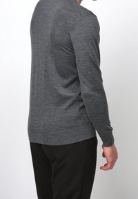 Grauer Wollpullover mit langen Ärmeln, gerippten Bündchen und geradem Saum. Die Textur wirkt glatt und weich, vor einem hellen Hintergrund.