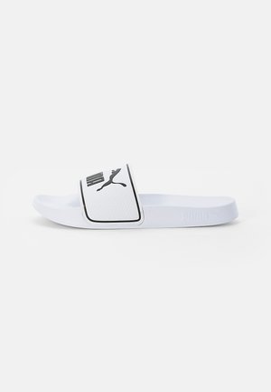 Bela drsna sandal s teksturiranim trakom, ki ima črn logotip Puma. Vsebuje gladek podplat in minimalističen dizajn.