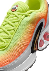 Basket de type Air Max avec une tige en maille dégradée allant du jaune vif à l'orange, accents noirs et une unité air visible dans le talon.