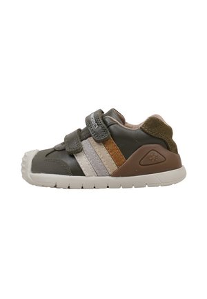 Zapatilla casual para niños en verde oliva con dos tiras de velcro, suela blanca y rayas laterales marrones y beige.