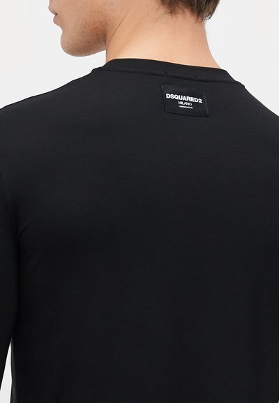 Juodas ilgomis rankovėmis marškinėlis, pagamintas iš lygaus audinio. Yra apvalus iškirpimas ir nugarinėje pusėje etiketė su "DSQUARED2 MILANO" prekės ženklu.