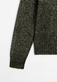 Dark green knitted sweater with a textured pattern. Features ribbed cuffs and hem, showcasing a chunky knit design.