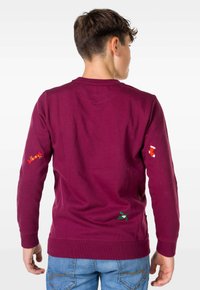 Bordo sweatshirt z vezenimi vzorci: sladkarije, nogavice in imele na rokavih. Mehka bombažna tkanina z zaobljenim izrezom.