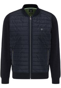 Giacca trapuntata blu navy con tessuto blu scuro uniforme su maniche e lati, chiusura zip frontale, due tasche laterali e colletto a costine.