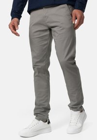 Szare chinosy o slim fit, wykonane z lekkiego materiału. Posiadają boczne kieszenie i są zestawione z białymi sneakersami dla kontrastu.