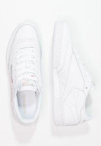 Baskets Reebok blanches dotées d'une tige en cuir lisse, de détails perforés, d'un bout arrondi et d'une semelle en caoutchouc plate. Le design est minimaliste avec un marquage subtil.