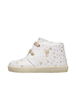 Chaussure pour tout-petit blanche avec motif de cœur en paillettes dorées, lacets beiges et semelle texturée beige, vue de côté sur fond blanc.