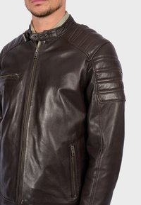 Hnědá kožená motorkářská bunda s předním zipem, žebrovanými detaily na ramenech a dvěma zipovými kapsami. Hladká textura a přiléhavý design.