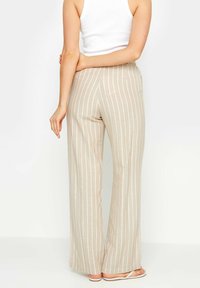 Beige, wijde broek met verticale witte strepen, gemaakt van een lichte stof. Glad textuur en elastische tailleband voor comfort.