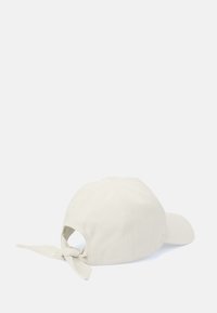Vit bomullshatt med en knuten tygdetalj bak, böjd skärm och sexpaneldesign. Enkel färg med en slät yta.